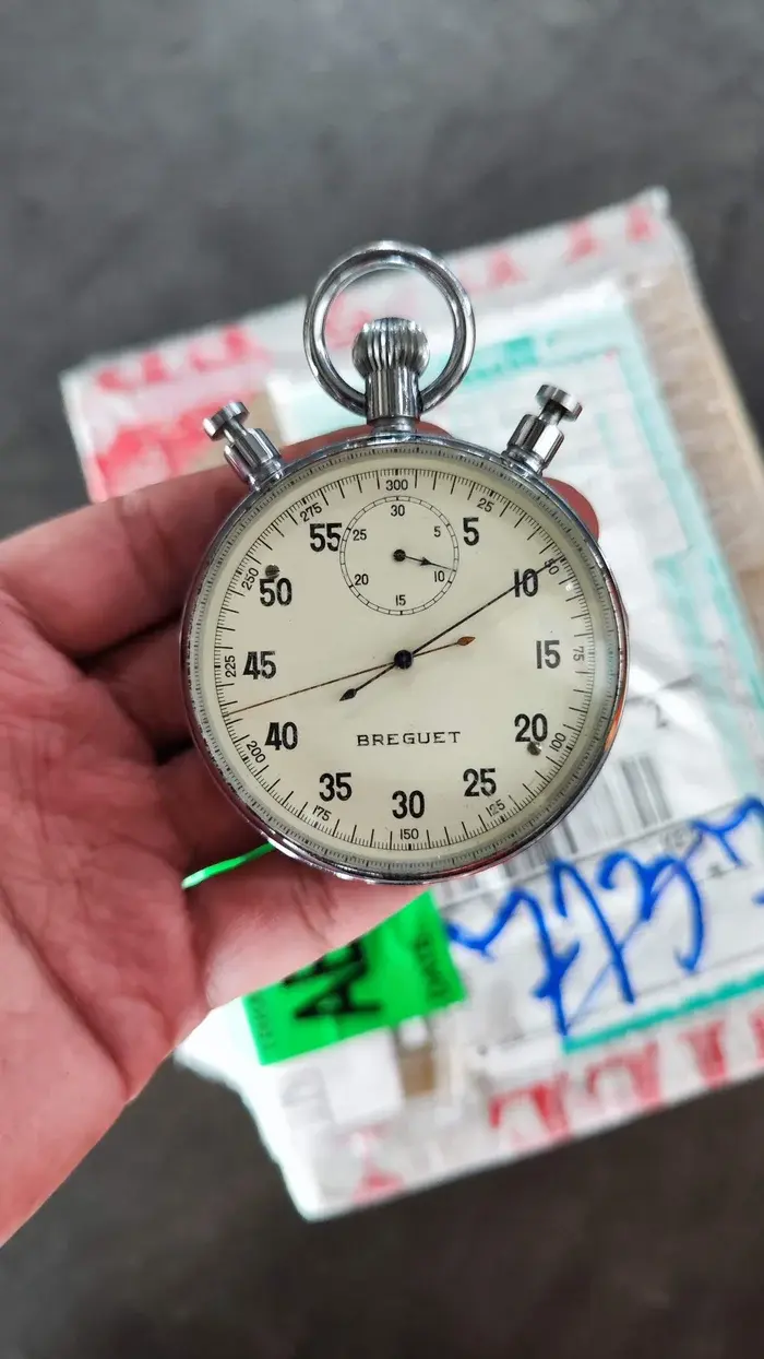 Hands inspecting an imported stopwatch beside its parcel