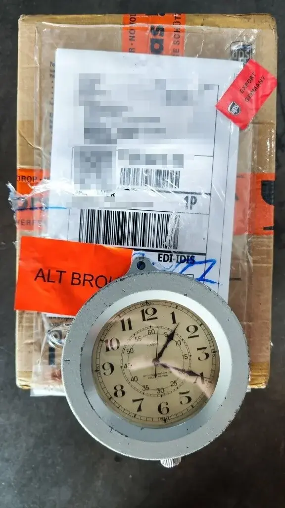 An imported clock checked beside its courier parcel, with address details concealed